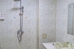 Un baño con ducha, lavamanos y espejo.