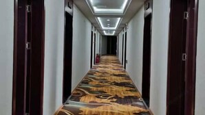 A long hallway with patterned carpet, doors on both sides, and recessed lighting on the ceiling. - Yintai Hotel (Menglian)