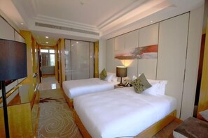 A hotel room with two beds, a TV, and a large painting on the wall.
