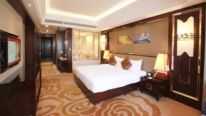 A hotel room with a large bed, a wooden headboard, a nightstand, a lamp, and a painting on the wall.