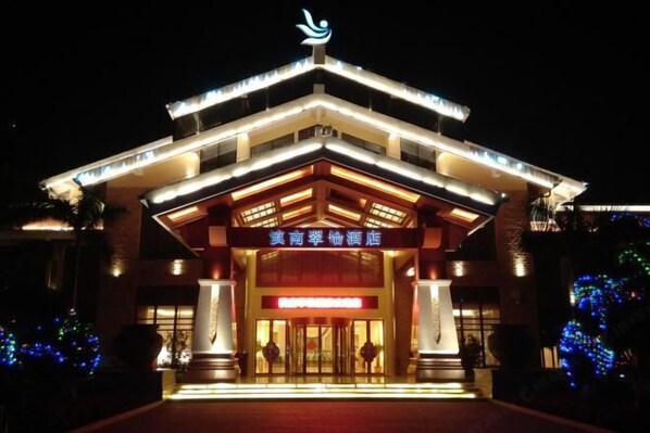 A hotel entrance with a modern design, featuring a prominent sign and illuminated entryway.