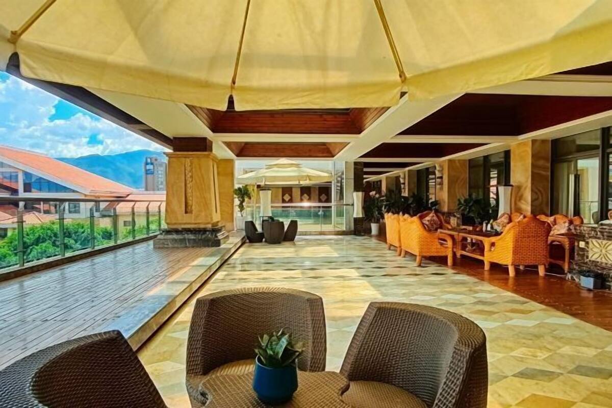 A spacious indoor area with a checkered floor, wicker furniture, and a large umbrella providing shade.