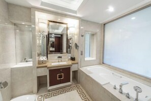 A modern bathroom with a large mirror, two sinks, a bathtub, and a patterned floor.