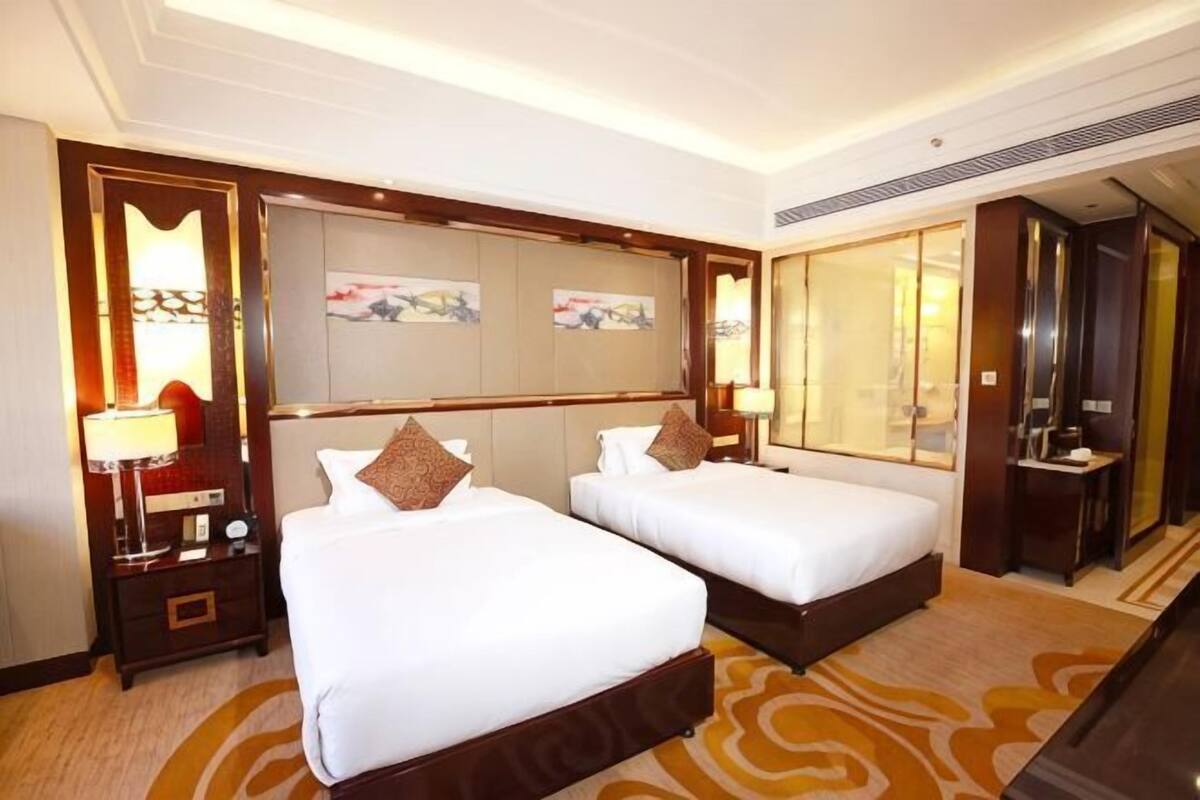 A hotel room with two beds, a large mirror, and a view of the city.