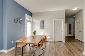 A dining area with a wooden table and chairs, a potted plant, and a wall-mounted bicycle. - Prime Location | Walkable to Belmont & Music Row (Nashville)