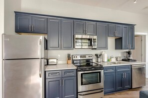 Une cuisine moderne dotée d’appareils électroménagers en acier inoxydable, de meubles de couleur bleu foncé et d’un îlot central.