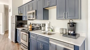A modern kitchen with grey cabinets, stainless steel appliances, and a coffee maker.