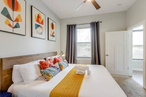 Ein Hotelzimmer mit Bett, Deckenventilator, Fenster mit Vorhängen und Kunstwerken an der Wand.