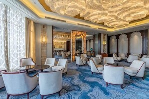 A hotel lobby with a patterned carpet, multiple seating areas, and a decorative ceiling. - Grand New Century Hotel (Zhangshu)