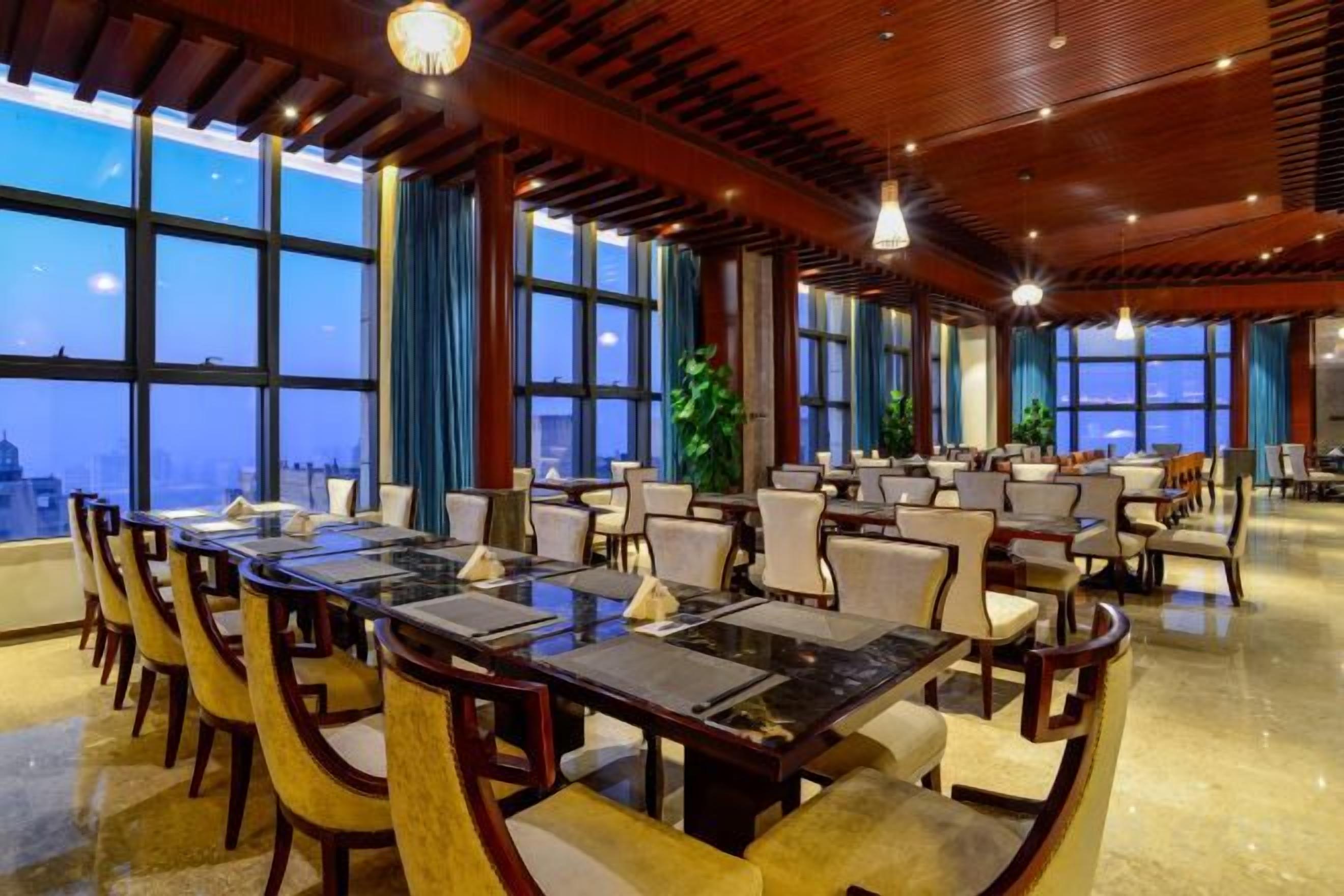 A spacious conference room with a long table and chairs, large windows, and a city view.