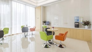 A modern hotel lobby with a reception desk, seating area, and large windows.