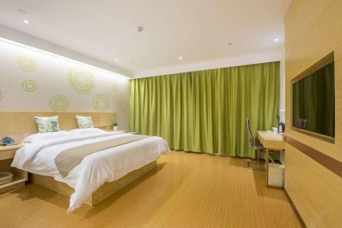 A hotel room with a bed, a desk, and a large window with curtains.