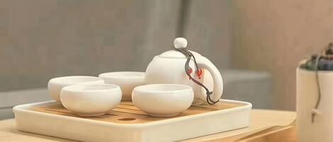 A white teapot with a lid and four white teacups on a tray.