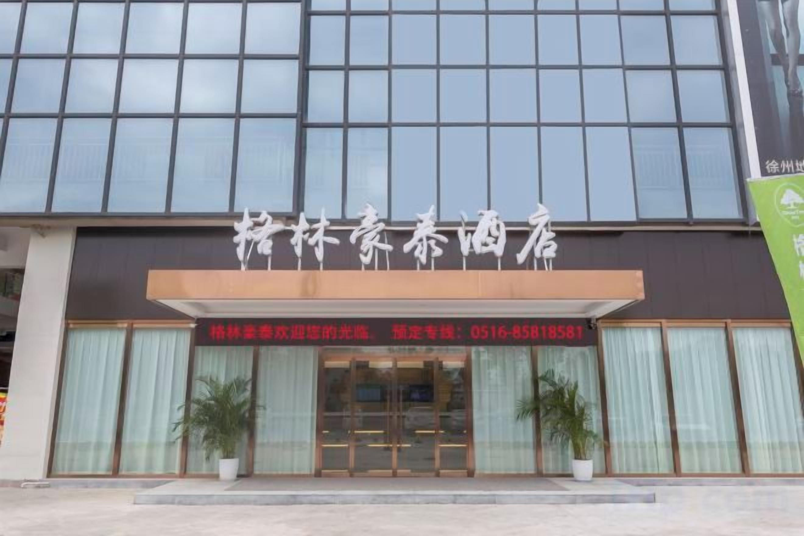 Un hotel con fachada moderna, amplios ventanales y una entrada destacada con una recepción.