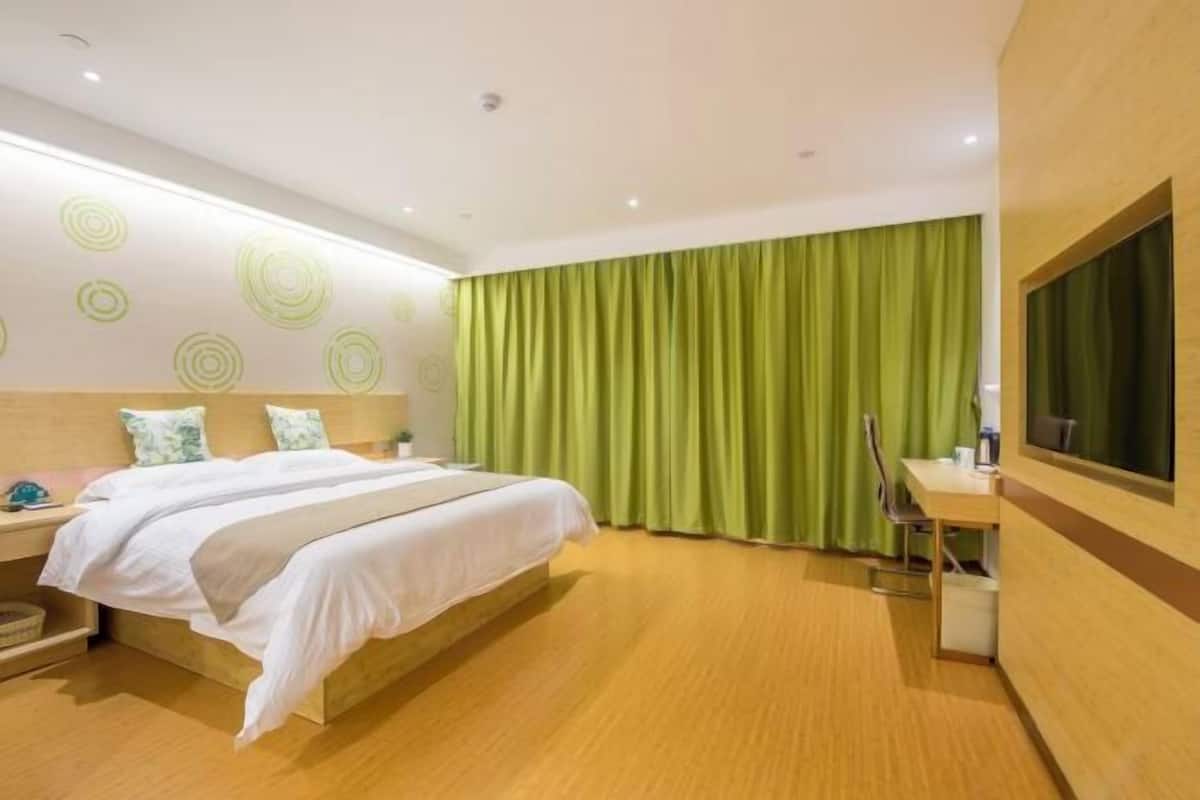 A hotel room with a bed, a desk, a chair, and a TV.