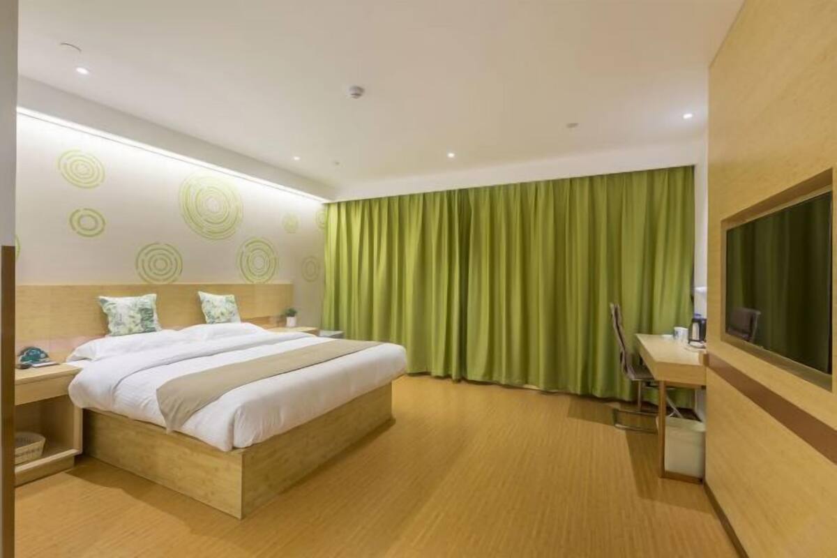 A hotel room with a bed, a desk, a chair, a window, and a curtain.