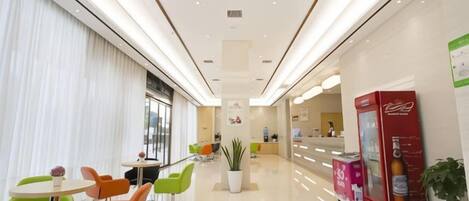 A hotel lobby with seating areas, a reception desk, and a Coca-Cola refrigerator.