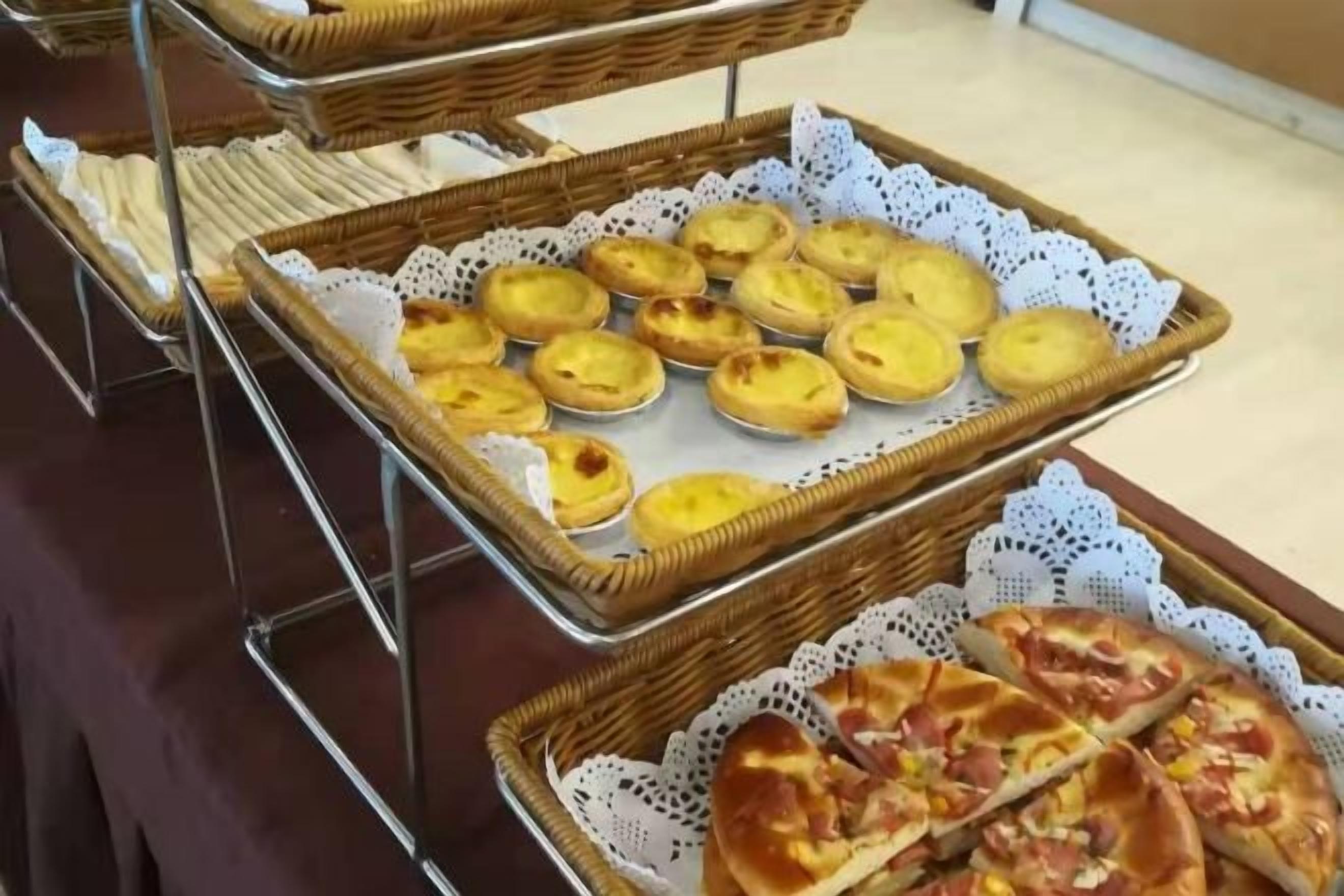 Noutopöytä, jossa on tarjottimilla erilaisia ruokia, kuten leivonnaisia ja pizzaa.