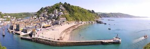 Un pueblo costero con una colina destacada, un puerto deportivo y un muelle.