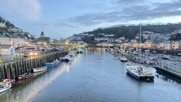 A harbor with numerous boats docked along the piers, surrounded by buildings and a clock tower.