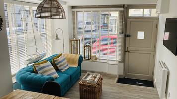 A cozy living room with a blue sofa, a wooden table, and a wicker basket.