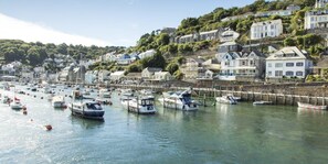 Un port où des bateaux sont amarrés, entouré de maisons situées sur une colline.