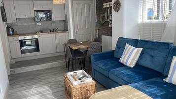 A compact living space with a kitchenette, a dining area, and a blue sofa with striped pillows.