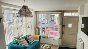 Una sala de estar acogedora con un sofá azul, una mesa de madera y una cesta de mimbre.