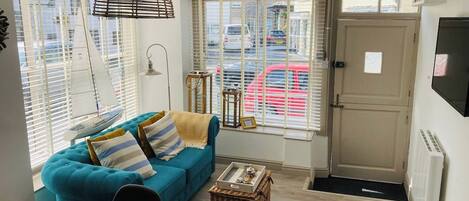 A cozy living room with a blue sofa, a wooden table, and a wicker basket.