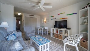A living room with a sofa, armchair, coffee table, TV, and decorative fish on the wall. - 1 Bedroom, Sleeps 4, Balcony w/ Ocean View (Ocean City)
