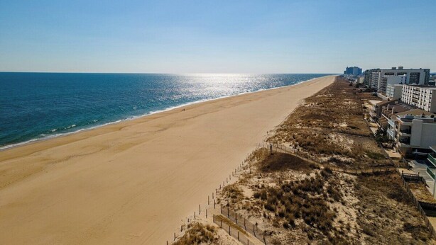 A beach with a sandy shore, a fence, and buildings in the background. - 1 Bedroom, Sleeps 4, Balcony w/ Ocean View (Ocean City)