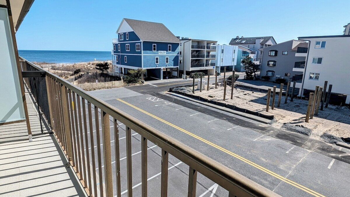 Ein Anwesen direkt am Strand mit Parkplatz, einem Balkon mit Geländer und Gebäuden mit Balkonen mit Blick auf den Strand.