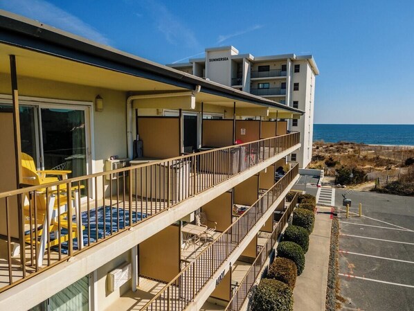 A multi-story hotel with balconies, a parking lot, and a view of the beach. - 1 Bedroom, Sleeps 4, Balcony w/ Ocean View (Ocean City)