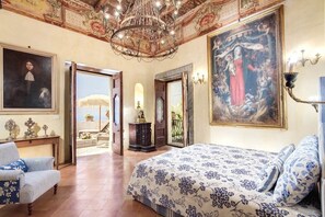 A spacious bedroom with a large bed, a chandelier, and a painting of a religious scene. - Villa San Giacomo - Unique Villa in Positano (Positano)