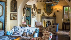 Une pièce dotée d’une cheminée, d’un lustre et de divers tableaux encadrés accrochés aux murs.