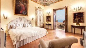 Une chambre spacieuse avec un grand lit, un plafond décoré et des œuvres d’art.