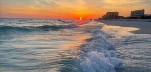 A beach with waves at sunset, buildings in the background, and a clear sky. - Renovated 2022 Oceanview Studio TOG BEACHCHAIRS UMBRELLA thru October (Panama City Beach)