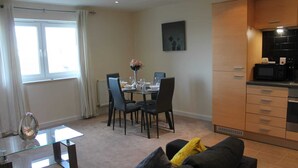 A compact living space with a dining area, kitchenette, and a sofa with cushions. - Remarkable 2-bed Apartment in Reading (Reading)