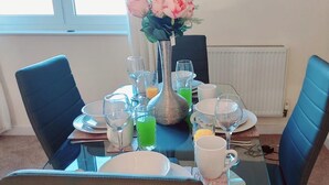 A dining table set for four with chairs, a vase with flowers, and various glasses and plates. - Remarkable 2-bed Apartment in Reading (Reading)