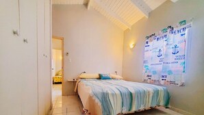 Un dormitorio con una cama, una mesita de noche y un cartel de temática playera en la pared.