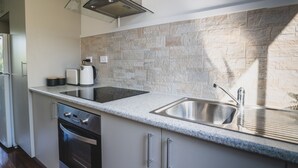 A modern kitchen with granite countertops, stainless steel appliances, and a stone backsplash. - RYDER FLATS UNIT 2 - Close to Beaches (South West Rocks)