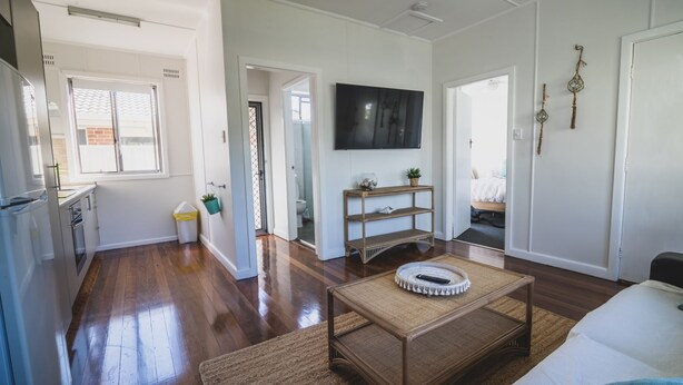 A modern living room with hardwood flooring, a flat-screen TV, a coffee table, and a sofa. - RYDER FLATS UNIT 2 - Close to Beaches (South West Rocks)