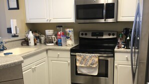 A kitchen with white cabinets, a stainless steel stove, a microwave, and a refrigerator. - Beautiful beach condo for rent (Panama City beach)