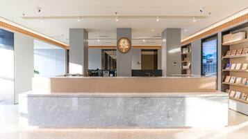 A modern reception desk with a marble counter, wooden paneling, and a digital display.