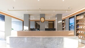 A modern reception desk with a marble counter, wooden paneling, and a digital display.