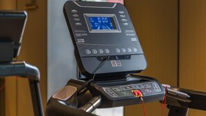 A treadmill with a digital display, control buttons, and a QR code.