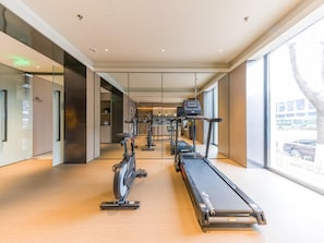 A modern gym with cardio equipment, a walking track, and large windows offering a view of the outside.