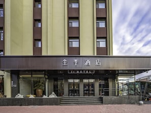 A hotel with a modern facade, a prominent entrance with glass doors, and a sign indicating it is a hotel.