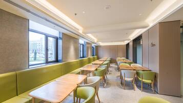 A modern conference room with long tables and green chairs, large windows, and a neutral color scheme.