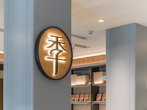 A modern interior with a wall-mounted sign featuring Chinese characters, a ceiling with recessed lighting, and a section with framed pictures.